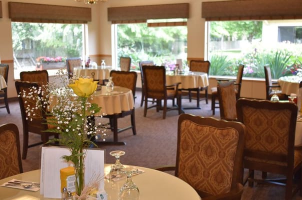 Dining area with tables set for meals and flowers.