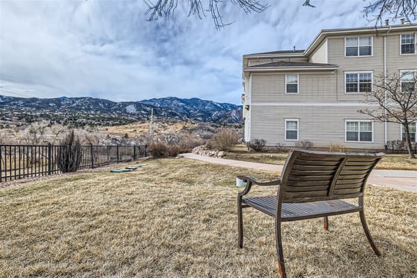 A bench overlooking a garden area and mountains in the background.