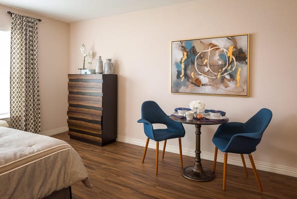 A well-decorated bedroom with a dining table and chairs, and an artistic wall painting.