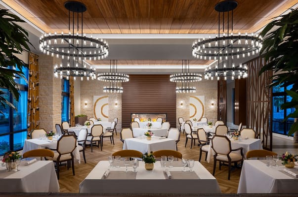 Stylish dining area featuring round tables, chandeliers, and a warm ambiance