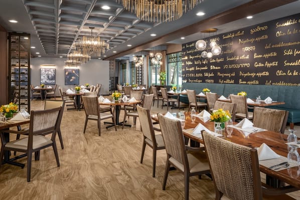 Elegant dining room with tables set for meals at Belmont Village Senior Living.
