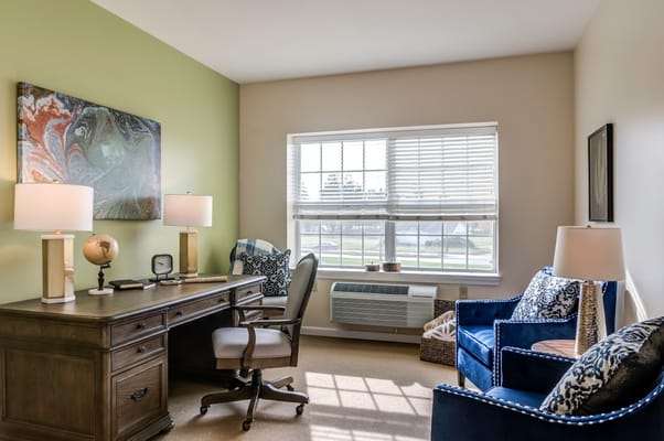 A cozy resident room with a desk and seating area