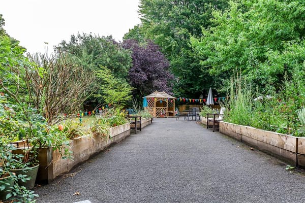 Pathway through a lush garden area with a gazebo