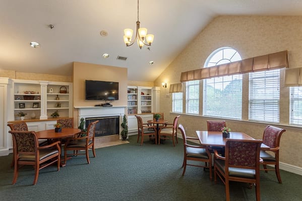 Common area with tables and chairs, bright windows