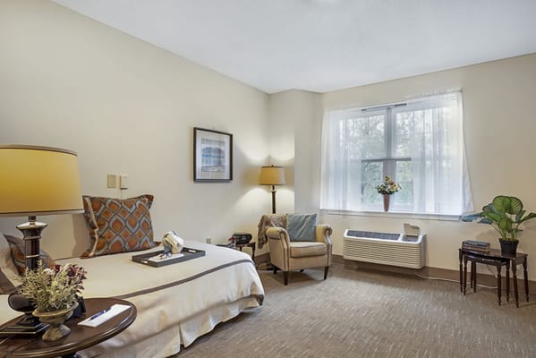 A cozy private resident room with a bed and chair