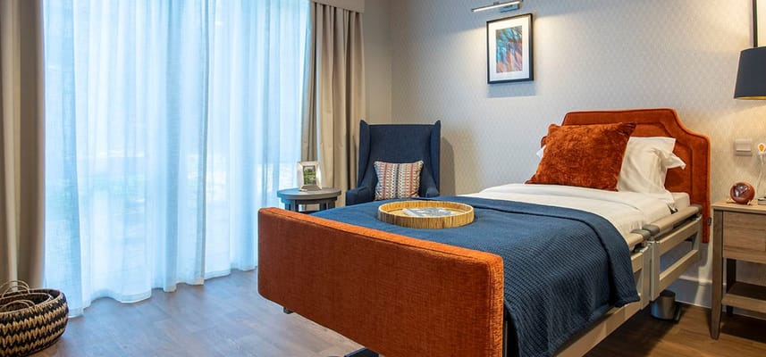 A well-furnished bedroom with a bed, armchair, and natural light