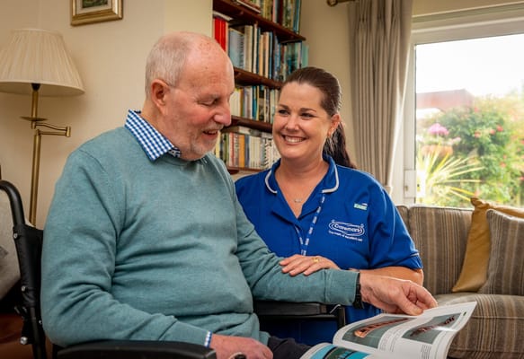 A staff member and a senior resident sharing a book together.