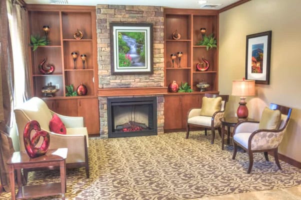 Comfortable seating area with a fireplace and decorative shelves.