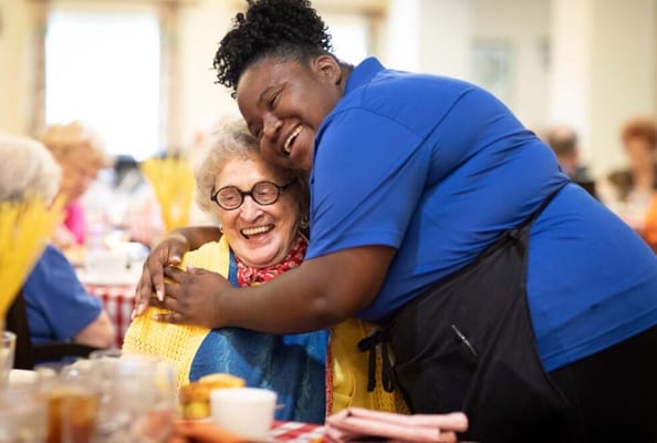 Staff member embracing a resident in the dining area