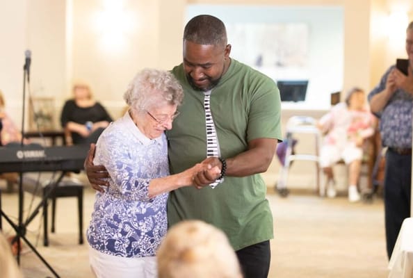 A resident dancing with staff in a common area
