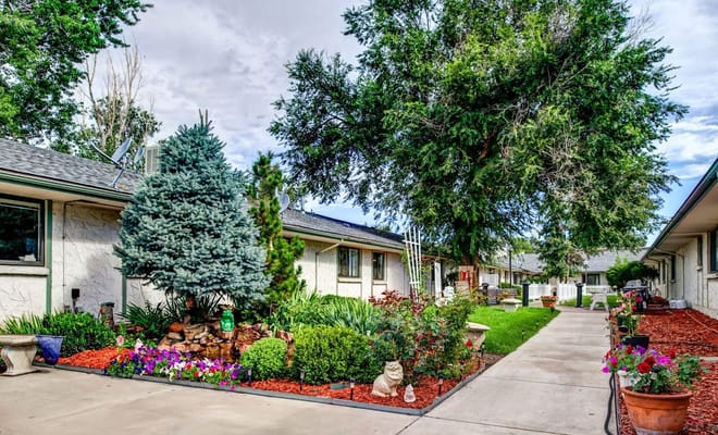 A landscaped garden with a pathway, trees, and flowers at Cedars Healthcare Center.