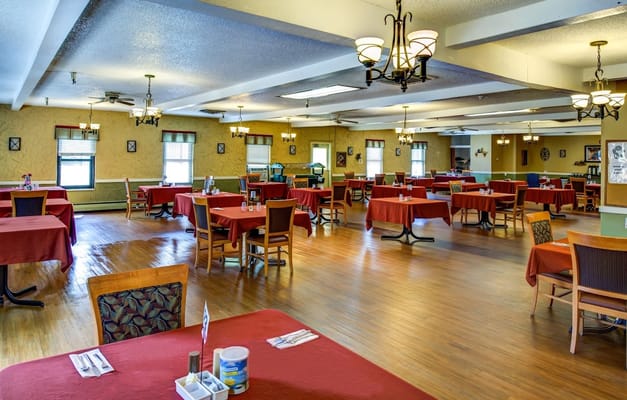 Spacious dining area with red tablecloths and wooden furniture