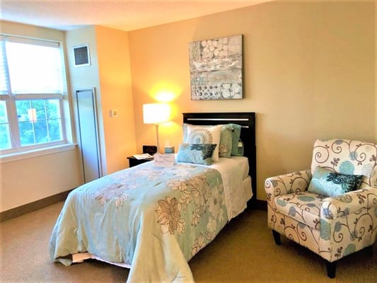 Cozy resident room with floral bedding and armchair