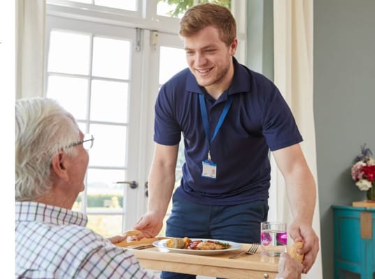 Staff serving a meal to a senior resident