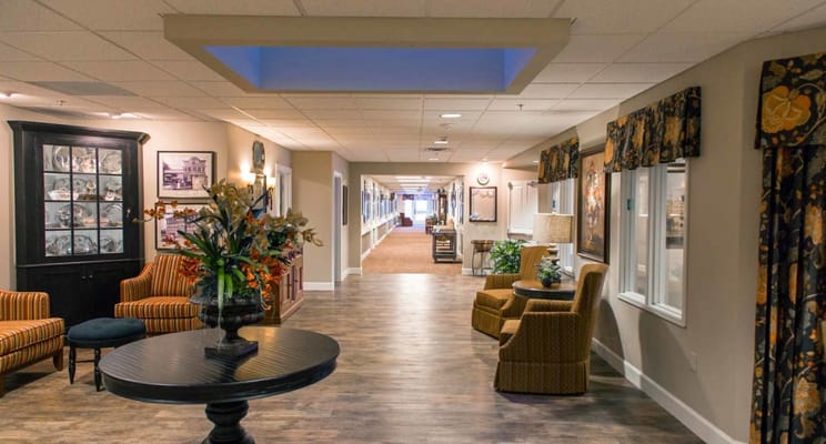 A well-lit hallway with seating and decorations at Copper Creek Inn Memory Care.