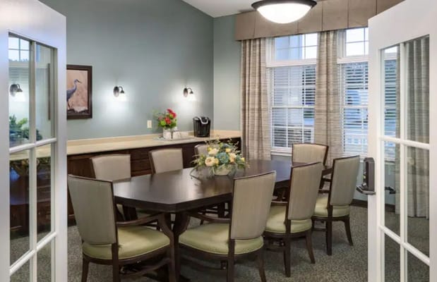 Well-lit dining room with a large table and seating for residents
