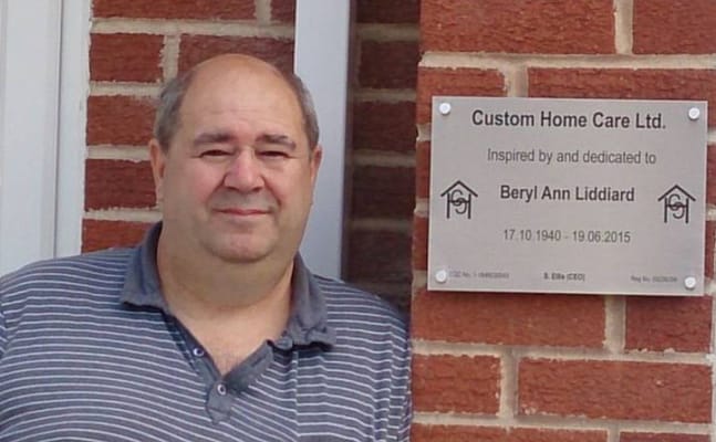 Person standing next to a plaque at Custom Home Care Ltd.