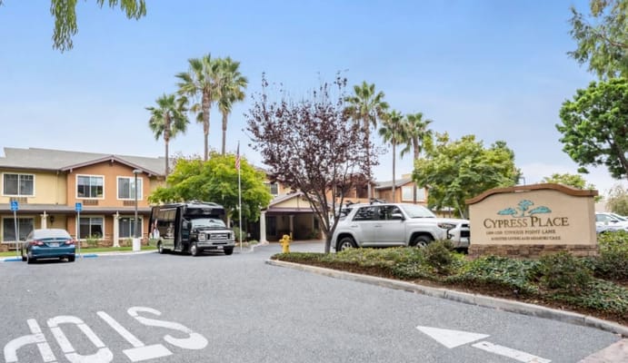 Entrance to Cypress Place with vehicles and palm trees.