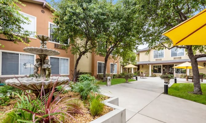 A serene courtyard featuring a fountain surrounded by greenery and patio seating.