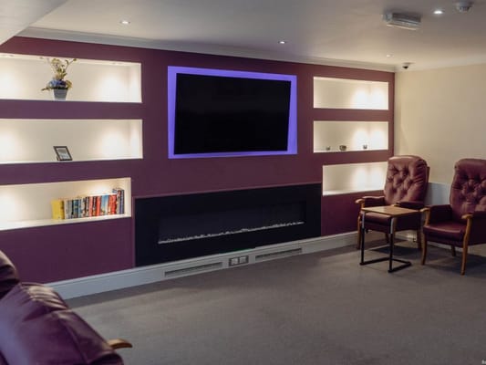 Lounge area with two brown chairs and a wall-mounted TV
