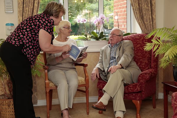 Two elderly residents and a staff member in a conversation