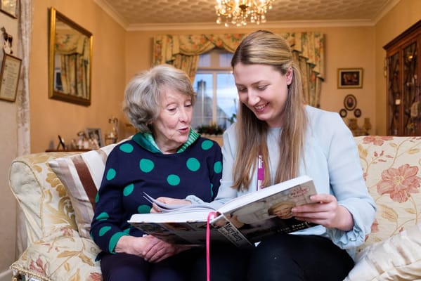 Staff member reading with a resident in a cozy common area