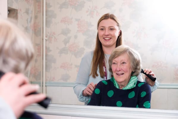 Staff member giving a hair grooming session to a resident