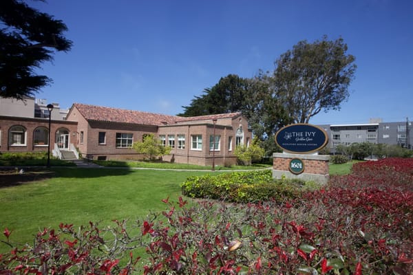 Exterior view of The Ivy at Golden Gate with garden and sign.