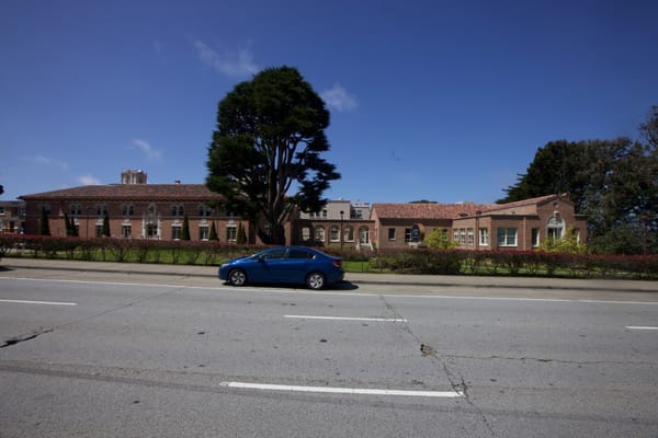 Exterior of The Ivy at Golden Gate facility with a tree and a parked car.