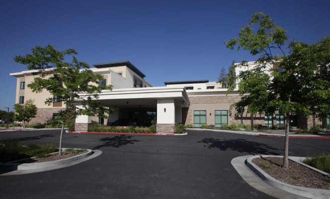 Front entrance of Belmont Village Senior Living Los Gatos surrounded by greenery