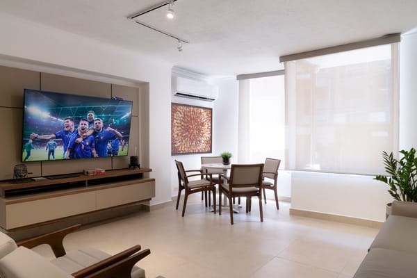 Bright common area with a TV showing a sports event