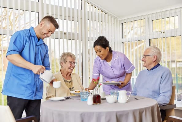 Staff serving food to residents in a dining area