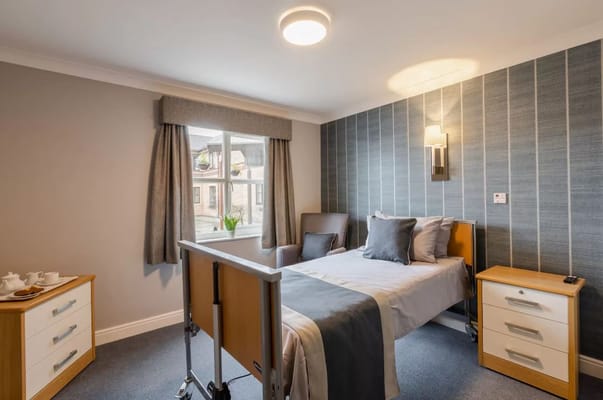 A well-furnished resident room with a bed and seating area