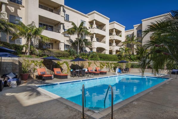 Outdoor swimming pool surrounded by lounge chairs and palm trees