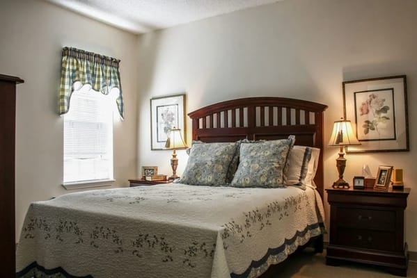 A well-decorated bedroom featuring a comfortable bed with floral pillows and bedside lamps.