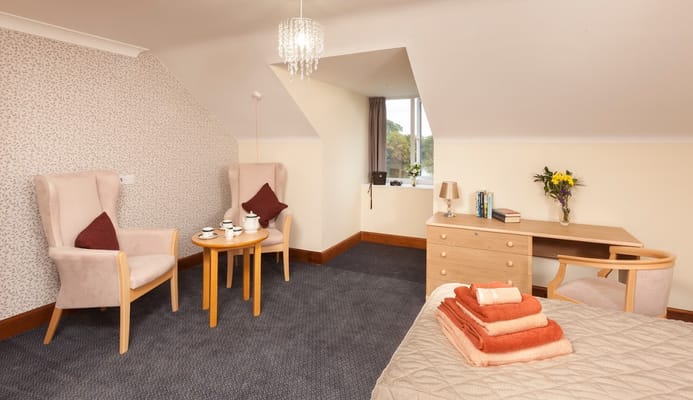 A cozy resident room with two chairs and a desk