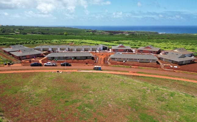 Aerial view of Lima Ola Family and Senior Apartments with surrounding green landscape and ocean in the background.