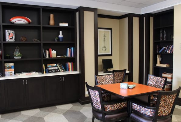 A cozy common area featuring a colorful table, chairs, and a bookshelf.