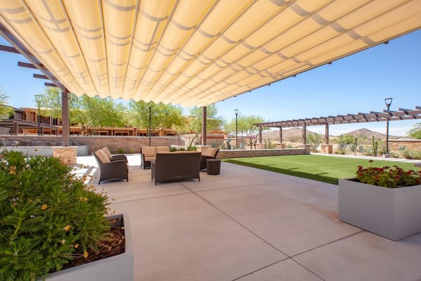 Outdoor patio area with shaded seating and greenery