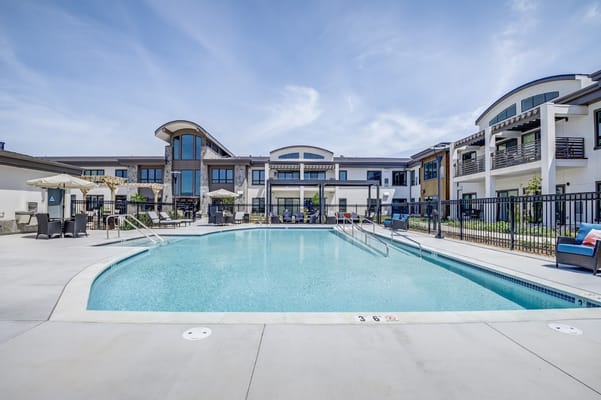 Pool area with lounge chairs and facility building in background
