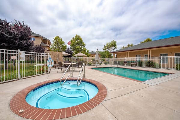 Outdoor pool area with a hot tub and greenery