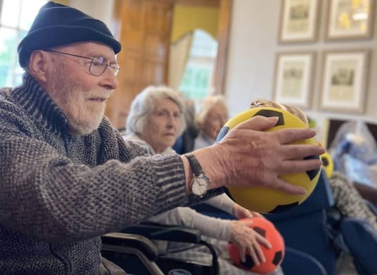 Residents engaging in a ball-passing activity indoors
