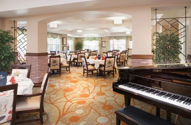 Elegant dining room with grand piano and tables set for meals