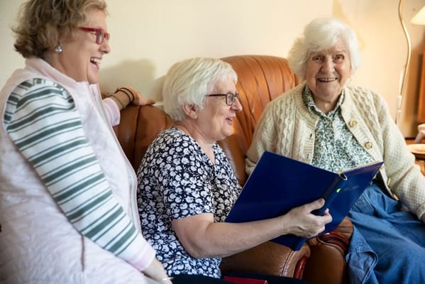 Three senior women engaged in conversation on a couch