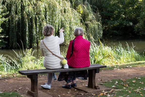 Two women sitting on a bench by a river