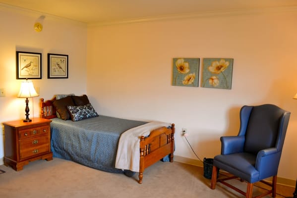 Cozy bedroom featuring a bed, blue chair, and artwork
