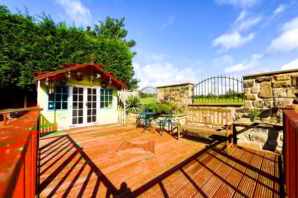 A bright outdoor space with a wooden deck and garden