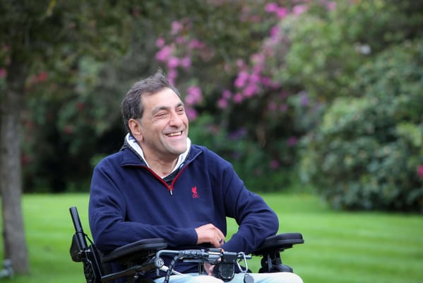 Man in a wheelchair smiling in a garden