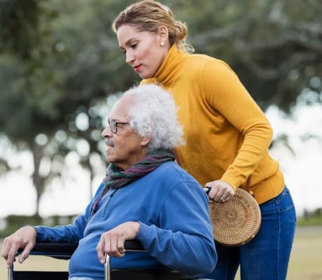 A caregiver assisting a resident in an outdoor area