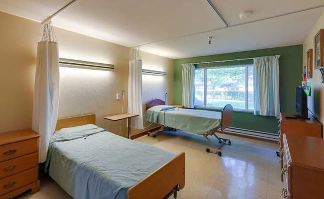 Two beds in a well-lit shared resident room